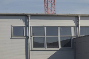 Çok sayıda penceresi ve belirgin bir şekilde arka planda konumlandırılmış bir vinç gösteren büyük bir bina var.