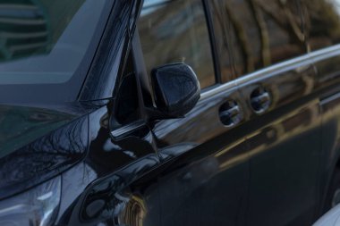 Bu yakın planda, parlak siyah bir araba görebilirsiniz. Pencerede görünen ağaçların güzel bir yansıması var, bu da derinlik katıyor.