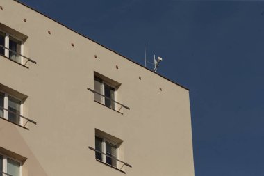 Üzerinde gelişmiş bir kamera olan yüksek ve etkileyici bir bina. Arka planda açık mavi bir gökyüzüne karşı kurulmuş.