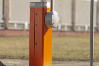 Kaldırımda bulunan turuncu renkli bariyerin detaylı bir yakın çekim görüntüsü, bir bina yapısının hemen önünde.