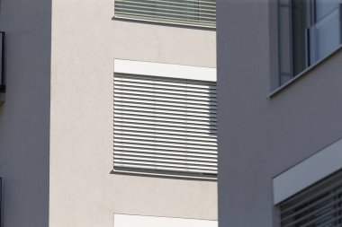 Bu, gizlilik ve ışık kontrolü için panjurlarla donatılmış sayısız pencereyle karakterize edilmiş büyük bir yapıdır.