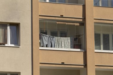 Çeşitli kıyafetlerin temiz havada kurumak üzere asıldığı ve canlı bir sahne yarattığı bir balkon.