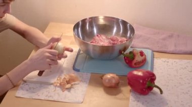 Bu yemek pişirme videosunda, bir kişi mutfakta takım çalışması yaparken ustalıkla bir yemek hazırlıyor, soğan ve sebze doğruyor.