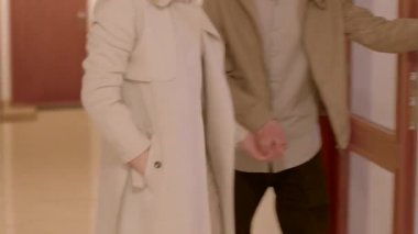 Ahşap kapılı büyüleyici bir koridor. Bir çift el ele dolaşır, sıcak dizayn edilmiş koridorda bağlarını sergilerler.