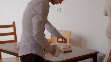 Sıcak bir yemek sahnesinde, yemek ve dizüstü bilgisayarlı bir masa etrafında bir adam ve bir kadın paylaşılan anlar boyunca bir bağ ve sıcaklığı vurguluyor.