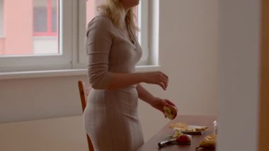 Sıcak bir mutfakta, bir kadın taze elmaları ustalıkla keser ve soyar, dingin bir atmosfer yaratır. Canlı meyveler yemek pişirmenin güzelliğini gösteriyor.