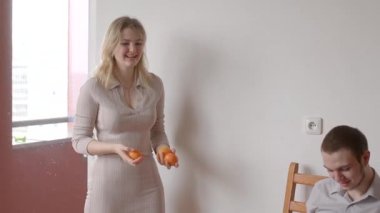 Bu video, bir kadının, elinde portakal tutan ve birlikte sıcak bir anı paylaşan bir adamla masaya oturduğu rahat bir oturma odasını gösteriyor.
