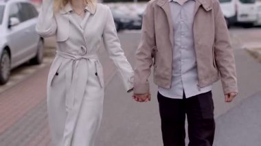Bir erkek ve bir kadın sokakta el ele yürüyor, birbirine eşlik ederek eğleniyorlar ve dışarıdaki güzel günün tadını çıkarıyorlar.