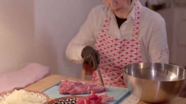 Önlüklü bir kadın, mutfakta eldivenle yemek pişiriyor, mutfak işine odaklanıyor.