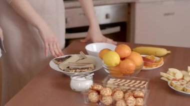 Sıcak bir mutfakta, bir adam sıcak bir hava katarak kahve koyar. Bir kadın içeri girer, güzel hazırlanmış yiyeceklerle gurur duyar, neşeli bir atmosfer yaratır.