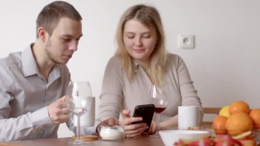 Bir adam ve bir kadın bir masada oturuyor, kahve ve sohbetin tadını çıkarıyorlar, aralarındaki cep telefonuna baktıklarında birbirlerine gülümsüyorlar.