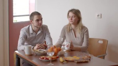 Bir çift yemek yiyor, basit bir masada meyve ve içecekleri paylaşıyor, keyifli bir ortam yaratıyor.