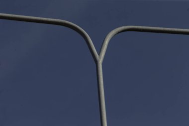 Açık mavi gökyüzüne karşı dik duran bir sokak lambası direğinin detaylı bir yakın görüntüsü, yapısını ve tasarımını gözler önüne seriyor.