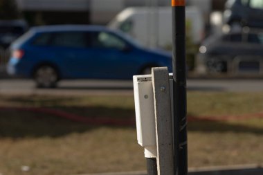 Mavi bir araba hızla kaldırımdaki bir parkmetrenin yanından geçiyor. Parlak tasarımını ve canlı rengini sergiliyor.