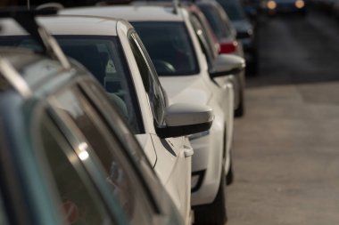 Gündüz vakti geniş bir otoparkta park edilmiş uzun bir sıra araba görülebiliyor. Bu da kentsel atmosfere neşe katıyor.