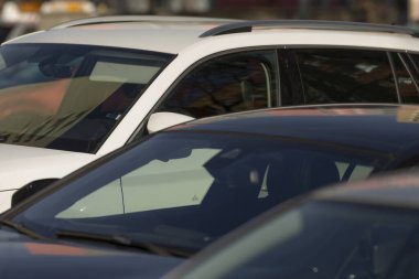 Geniş bir otoparkta düzgünce düzenlenmiş ve park edilmiş, çeşitli model ve renkleri gösteren uzun bir sıra araba var.