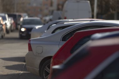 Geniş bir otoparka düzgün park edilmiş, farklı marka ve modelleri bir arada gösteren uzun bir sıra araba var.