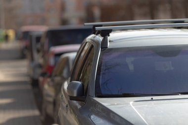 Yolun kenarına park edilmiş bir dizi araba, farklı otomotiv tipleri ve tasarımları gösteren renkli bir sahne yaratıyor.