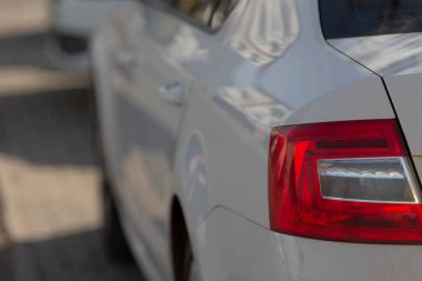 Bu parlak beyaz bir arabanın yakın plan görüntüsü çarpıcı kırmızı arka lambasını gösteriyor, mükemmel bir otomotiv tasarımı sergiliyor.