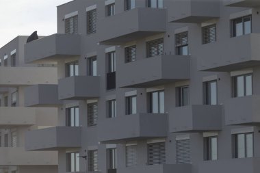Çağdaş mimari tasarım ve kentsel yaşamın sergilendiği, balkonların ve sayısız pencerenin yer aldığı uzun bir sıra modern apartman binaları.