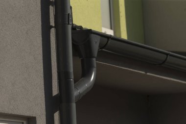 Bu, binanın yan tarafındaki yağmur oluğunun detaylı bir görüntüsü, yapısını ve işlevselliğini gösteriyor.