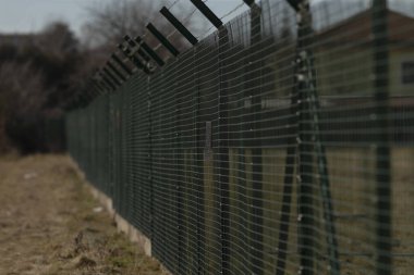 Bu resim, arka planda yer alan ve belirgin bir şekilde yapısını gösteren bir çitin ayrıntılı bir yakın görüntüsünü içerir.