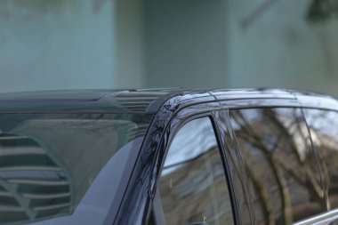 Gösterişli siyah bir araba büyük bir binanın önüne park edilmiş, tasarımı ve zarafeti sokaklardan sergileniyor.