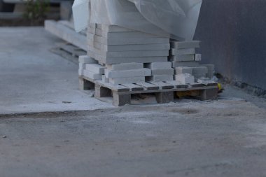 Şu anda büyük bir tuğla yığını, tuğlalara destek sağlayan sağlam bir ahşap paletin üzerinde rahatça dinleniyor.