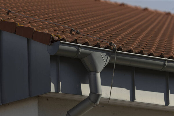 This image showcases a close seup view of a rain gutter installed on the roof of a residential house, highlighting its structural features