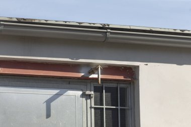 Bu fotoğraf, penceresini ve oluklarını belirgin bir şekilde gösteren bir binanın detaylı yakın çekim görüntüsünü yakalar.