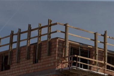 Şu anda inşaat sürecinden geçen sağlam bir tuğla bina, güvenlik için koruyucu bir ahşap korkuluk içeriyor