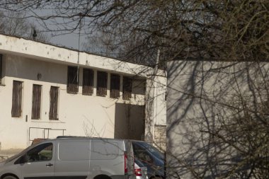 Şu anda bir binanın önüne park edilmiş beyaz bir minibüs var. Muhtemelen geçici park yeri için kullanılabilir durumda.