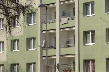 Çevresinde birden fazla balkon ve zarif sokak lambasının bulunduğu modern yeşil ve beyaz bir apartman dairesi kentsel manzarayı güçlendiriyor.