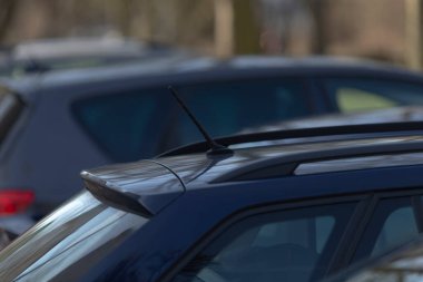 Mavi bir araba, çeşitli marka ve modellere sahip diğer arabalarla birlikte geniş bir otoparkta park halinde.