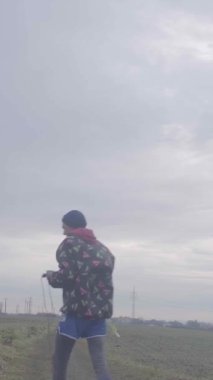 Bir birey, bulutlu bir arkaplan ile dolambaçlı bir yolda yürürken sıkıca bir ipe tutunuyor.