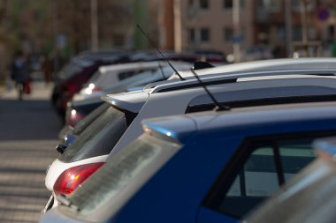 Bir otoparkta, düzenli bir sıra araba var. Düzgün bir şekilde dizilmiş ve park edilmiş. Belirlenmiş park yerlerini kaplıyorlar.