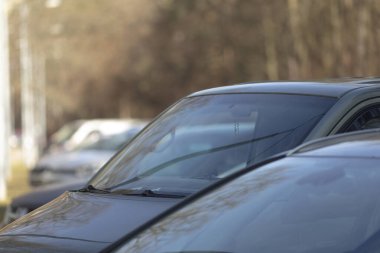 Şehirdeki bulanık kentsel arkaplan karşısında park halindeki arabaların yakın çekim perspektifi gösteriliyor