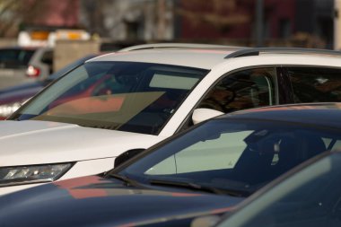 Kalabalık bir şehir ortamında diğer araçların arasına park edilmiş beyaz bir SUV var.