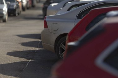 Şehir caddesi boyunca uzanan park halindeki uzun bir araba kuyruğu şehirde renkli bir zemin oluşturuyor.