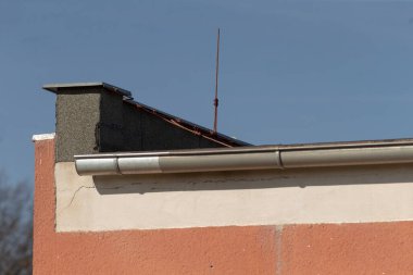 Duman temizleme için bir baca ve yağmur suyu drenajı için tasarlanmış bir oluk sistemi içeren eğimli bir çatı içeren bir yapı