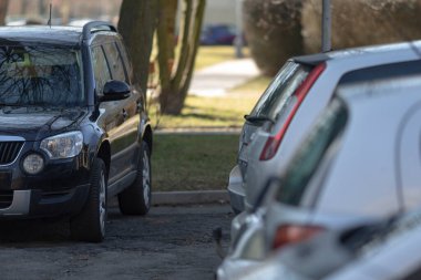 Geniş bir otoparkta düzenli olarak park edilmiş uzun bir sıra araba sahiplerinin dönmesini beklerken belirlenmiş yerleri işgal ediyor.