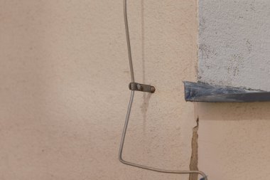 Sağlam bir metal tel, kentsel tasarımın kilit unsurlarını vurgulayan dokulu bir duvara sıkıca bağlanır.