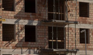 Şu anda inşaat halinde olan bir tuğla bina, gelişmekte olan çalışmaları desteklemek için iskelelerle çevrili, modern mimariyi gözler önüne seriyor.