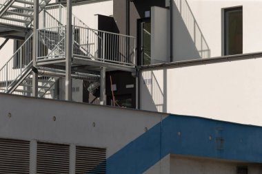 Mavi çatılı ve binanın yan tarafında kolay erişim için uygun merdivenleri olan çarpıcı beyaz bir bina
