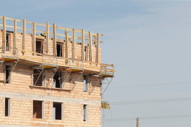Bir bina iskeleti ve arka planda çeşitli açık pencereleri olan aktif bir inşaat alanı
