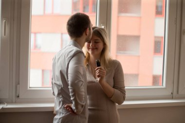 Bir çift, şehir ortamındaki bir pencerenin yanında sıcak ve sevgi dolu bir etkileşimi paylaşıyor.