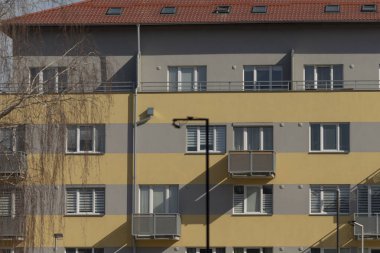 Yapısının tepesinde göz alıcı kırmızı bir çatıya sahip, genel estetik cazibesini arttıran ayırt edici sarı ve gri bir apartman dairesi.