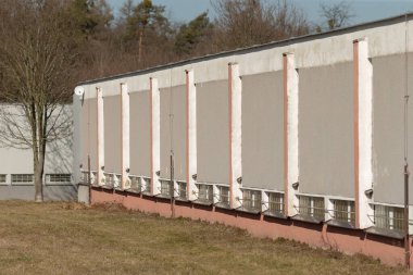 Geniş bir binanın dış görünümü çimenli bir arkaplana karşı birkaç havalandırma ünitesini gösterir