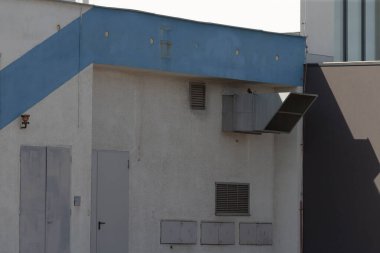 Yapı, kenarı boyunca uzanan belirgin mavi bir şeritle tamamlanmış beyaz bir dış görünüme sahiptir.