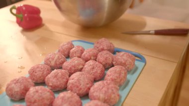 Bu videoda, bir şef köfte hazırlıyor, mavi bir kesim tahtasındaki malzemeleri karıştırıyor. Mavi bir tabakta sunuluyorlar, cazibelerini arttırıyorlar.